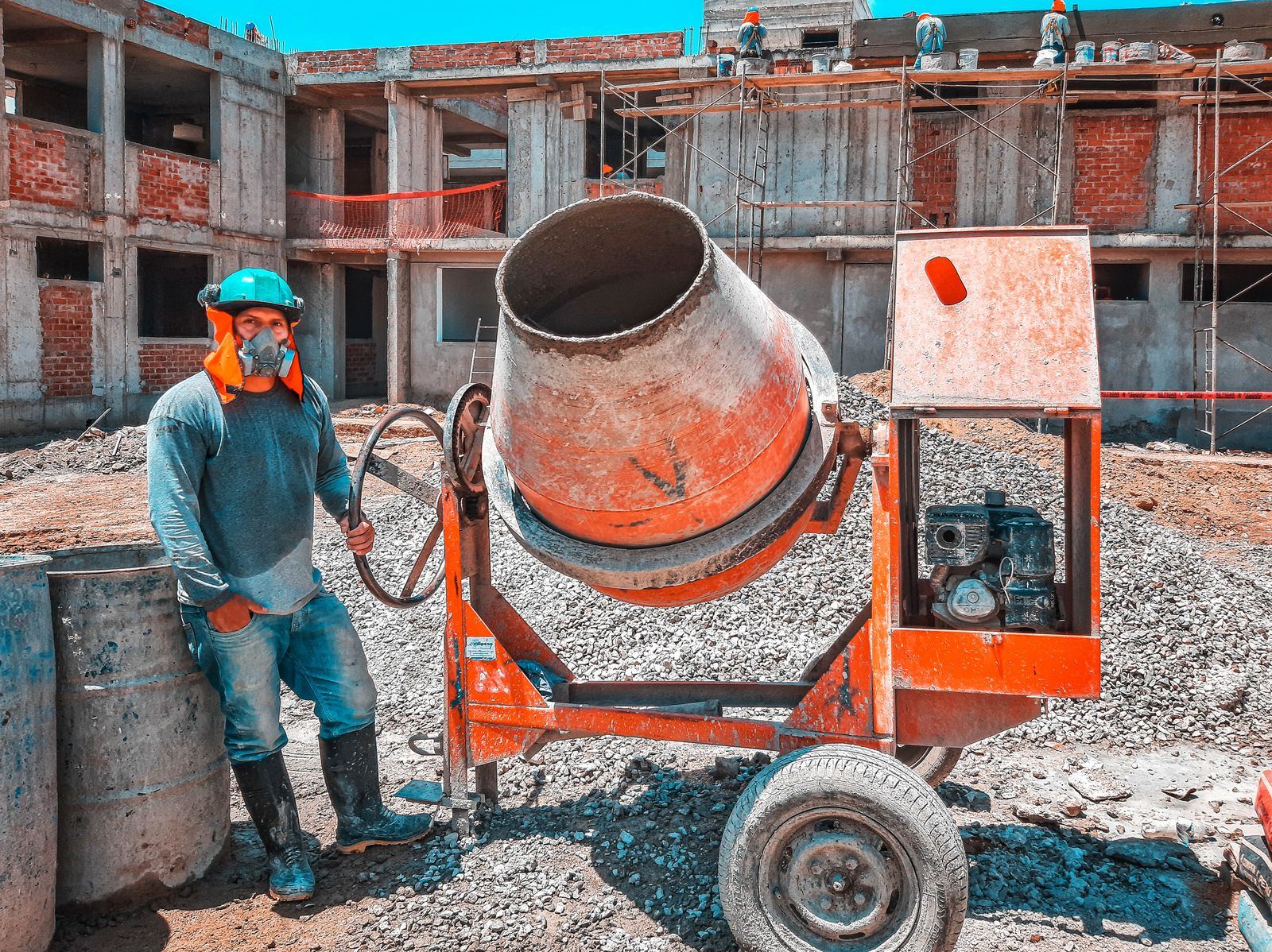 A worker in full PPE loading a cement mixer on site